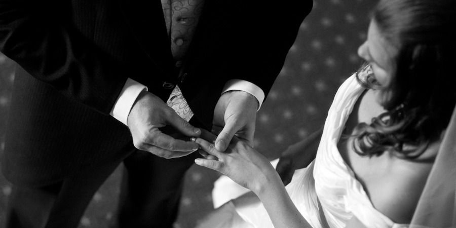 The groom puts the wedding ring on the finger of his bride, shot from above in Manchester Town Hall