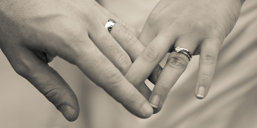 Bride and groom with fingers intertwined showing off their new wedding rings