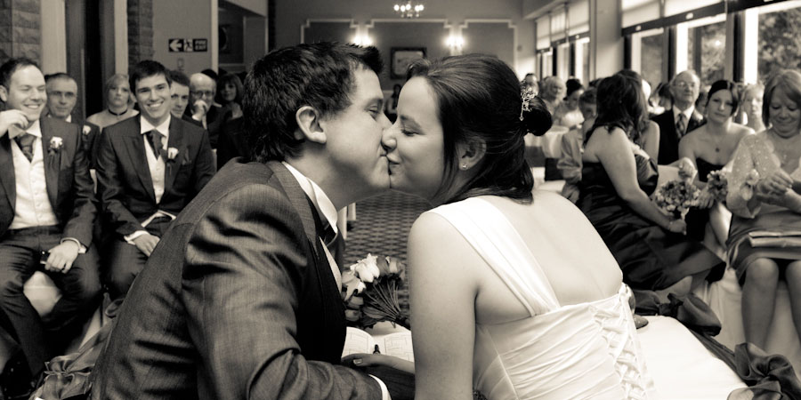 Bride and groom sneak a quick kiss after their wedding ceremony in Rochdale