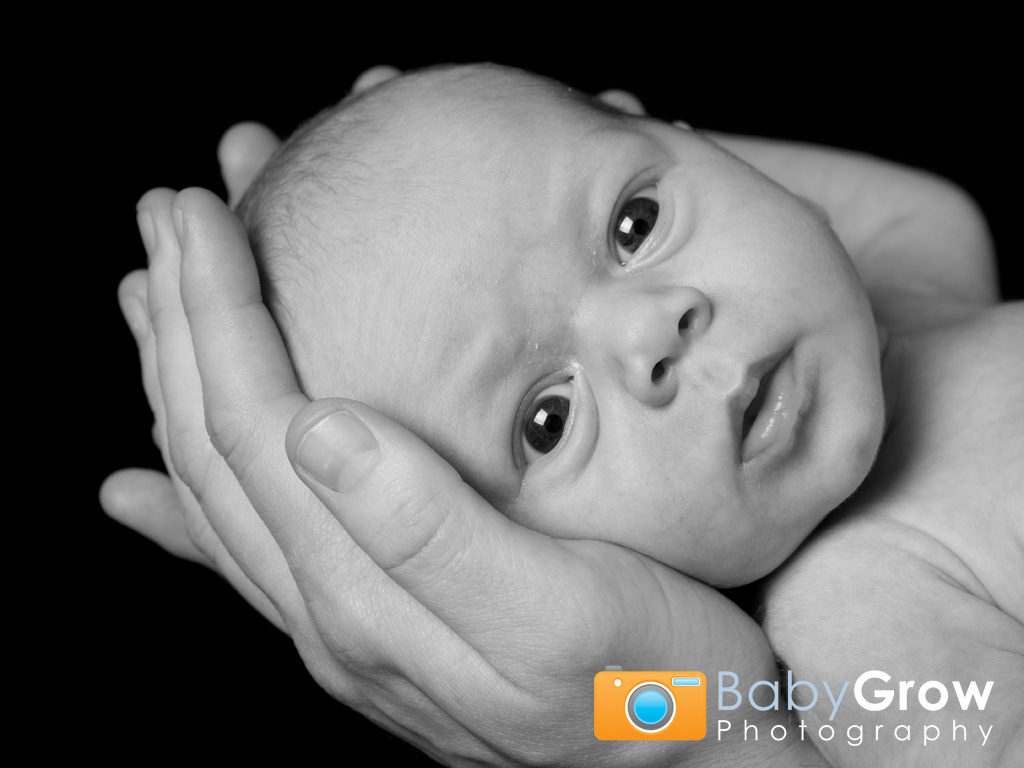 Baby's head being held in Dad's hands